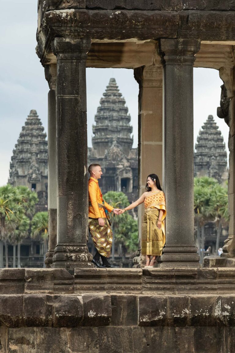 Creative Angkor Wat pre wedding photography with couple framed in ancient temple windows wearing traditional Cambodian clothing