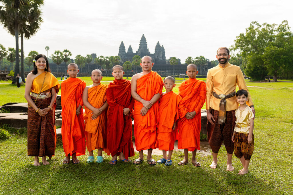 International visitors wearing Cambodian traditional dress with Buddhist monks at Angkor Wat.