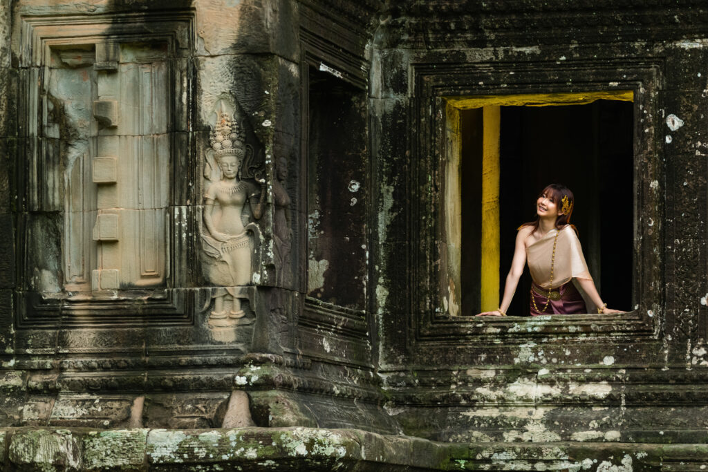 Woman framed by ancient Angkor Wat architecture during a traditional Cambodian dress photoshoot
